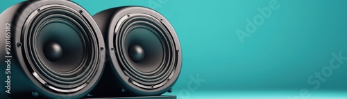 modern audio speakers against a vibrant turquoise background, showcasing sleek design and deep bass potential.