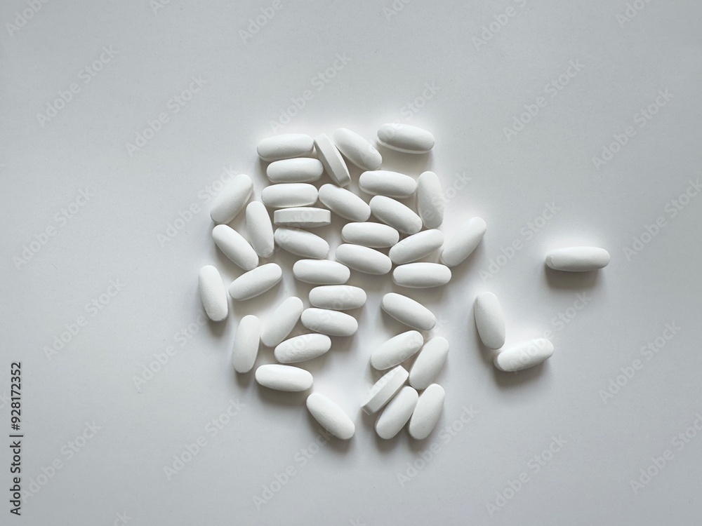 White oval tablets on a plain white background, minimalistic simplicity. Vitamins. White oval tablets on a plain white background, minimalistic simplicity. Vitamins.