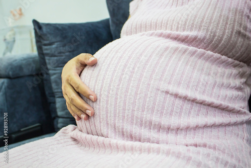 Close-up of pregnant woman touching her belly, A large belly of a woman in the last months of pregnancy.