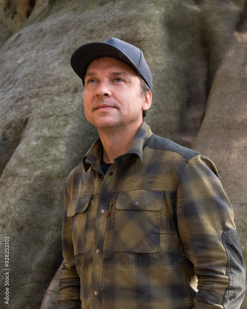 Fototapeta premium .Portrait of happy middle aged male traveler in plaid shirt. Enjoying nature while hiking in mountainous area. Healthy lifestyle, hiking, adventure. Saxon Switzerland, Germany