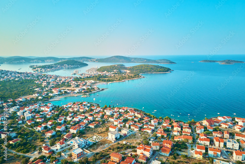 Aerial view of coastal town with colorful buildings near sea coastline. Touristic city for summer vacation with red roof houses and Islands in Adriatic sea. Panoramic view of Rogoznica town in Croatia Aerial view of coastal town with colorful buildings near sea coastline. Touristic city for summer vacation with red roof houses and Islands in Adriatic sea. Panoramic view of Rogoznica town in Croatia