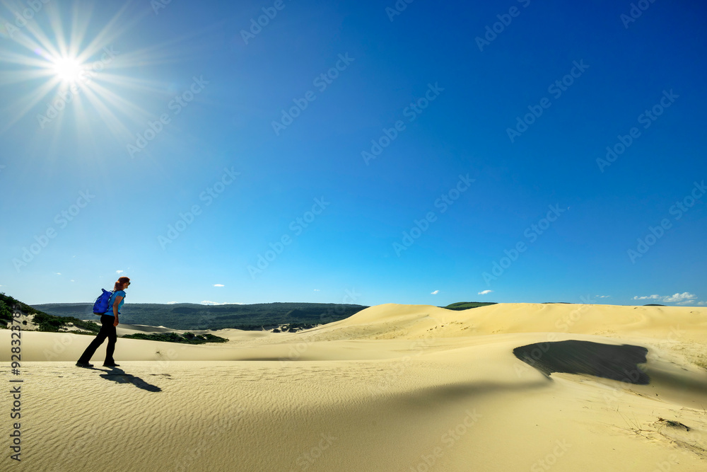 Woman walking on sand dunes under blue sky at sunny day in Eastern Cape, South Africa Woman walking on sand dunes under blue sky at sunny day in Eastern Cape, South Africa