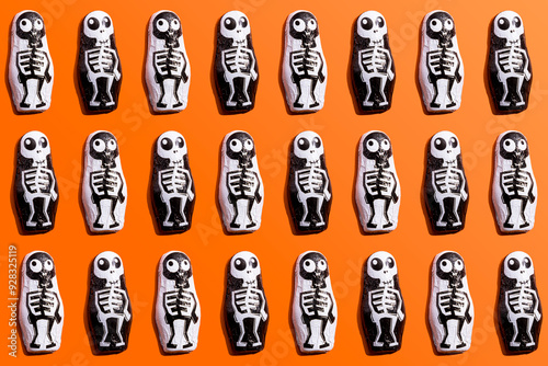 Pattern of rows of Halloween candy with skeleton wrapping against orange background photo