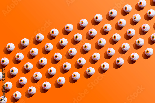 Pattern of rows of Halloween candy with eyeball wrapping against orange background