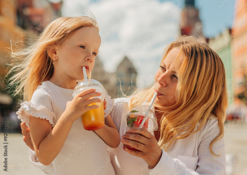 Mother and daughter enjoying lemonade on street Mother and daughter enjoying lemonade on street