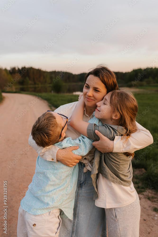 Children embracing mother standing near meadow Children embracing mother standing near meadow