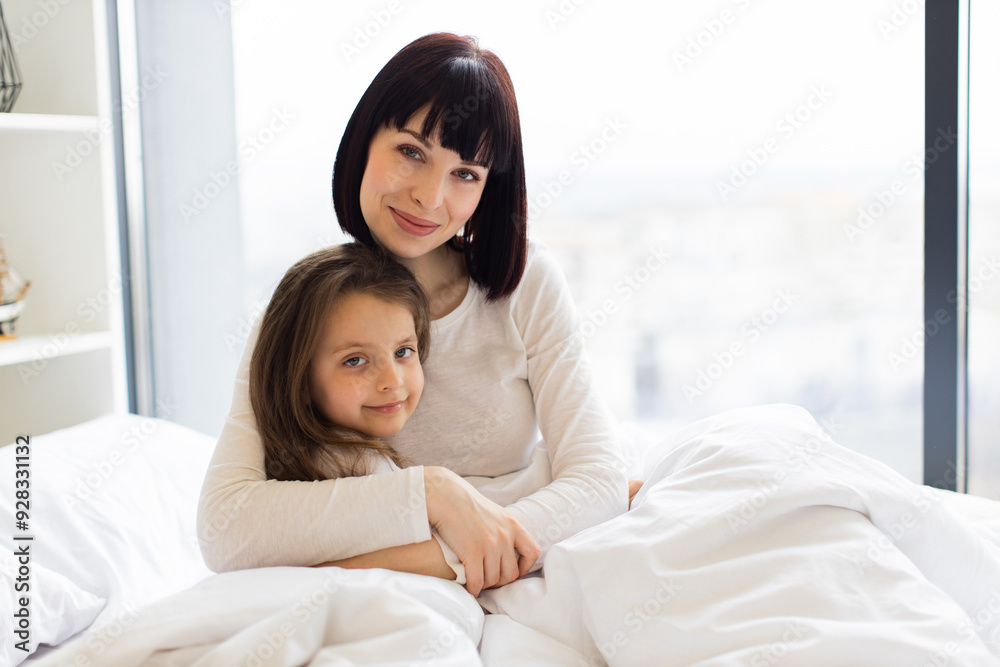 Mother and daughter hugging in bed. Loving family moment captured with mother embracing child. Cozy home atmosphere with warm bonding between parent and child. Mother and daughter hugging in bed. Loving family moment captured with mother embracing child. Cozy home atmosphere with warm bonding between parent and child.