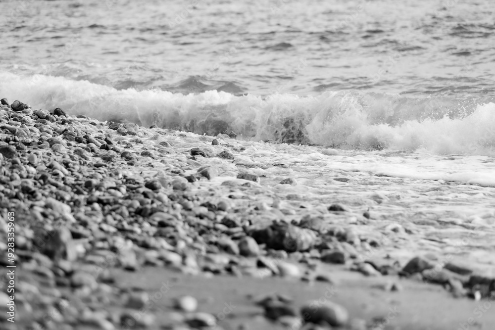 Pebbles on beach and sea water, black and white Pebbles on beach and sea water, black and white