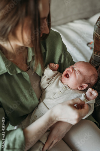 Mother holding crying baby in arms at home photo