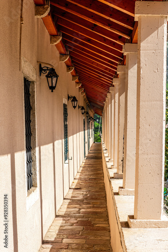 long gallery passage from a balcont syde of building to outdoor with beautiful white columns, windows and wooden brown roof. Vintage architecture concept photo