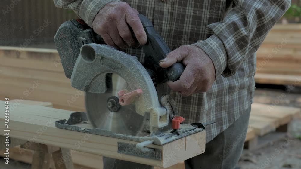 Close-up of an elderly man's hands with a circular saw. The man skillfully operates a circular saw to cut wood in an outdoor workshop. Close-up of an elderly man's hands with a circular saw. The man skillfully operates a circular saw to cut wood in an outdoor workshop.