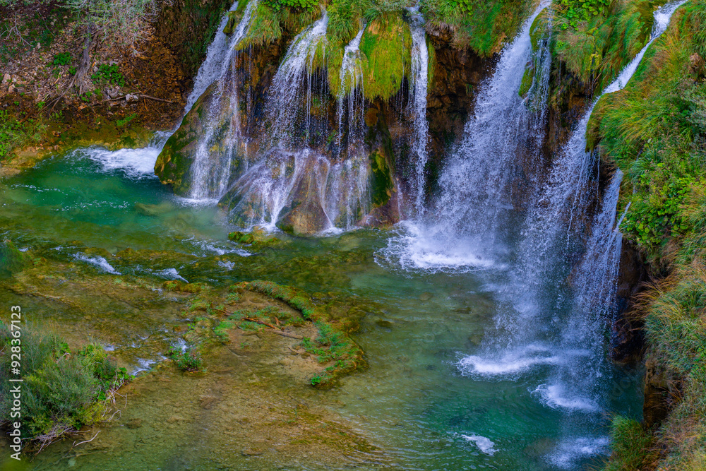 Obraz premium Waterfalls in the forest flowing into lakes. Tourists visit famous Plitvice park in Croatia. Mountain streams with clear water. Waterfalls of Plitvice Lakes on a summer day.