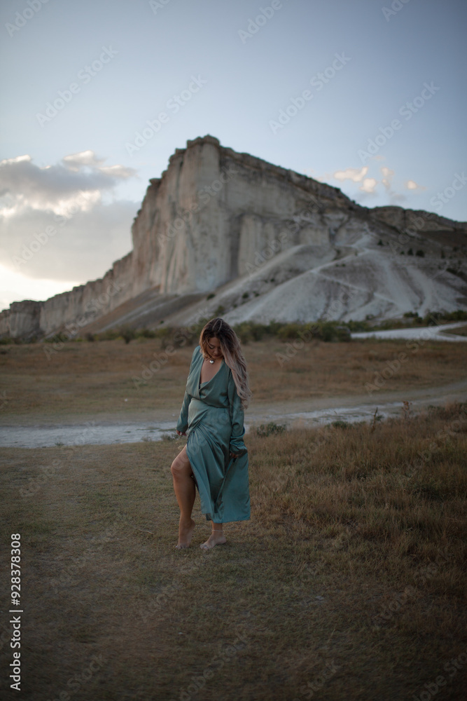 A woman plus size dressed in a dress walking against the background of a white mountain. Beautiful girl with a long hair developing in the wind travels A woman plus size dressed in a dress walking against the background of a white mountain. Beautiful girl with a long hair developing in the wind travels