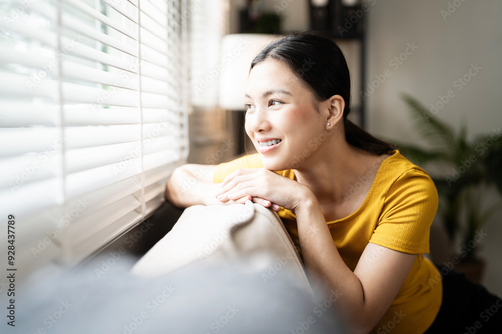 Happy young woman sitting on sofa at home and looking outside. Portrait of comfortable woman relaxing on couch. Portrait of beautiful girl smiling and relaxing during autumn. Happy young woman sitting on sofa at home and looking outside. Portrait of comfortable woman relaxing on couch. Portrait of beautiful girl smiling and relaxing during autumn.