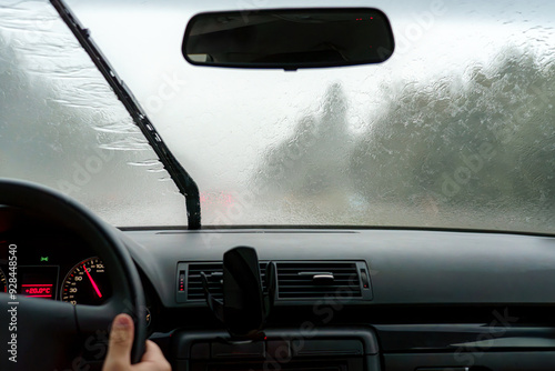 The car's windshield wipers work during rain while driving on the road.