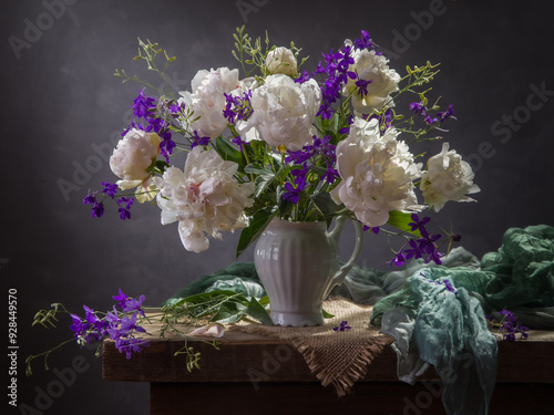 Still life with white peonies and delphinium on a dark background