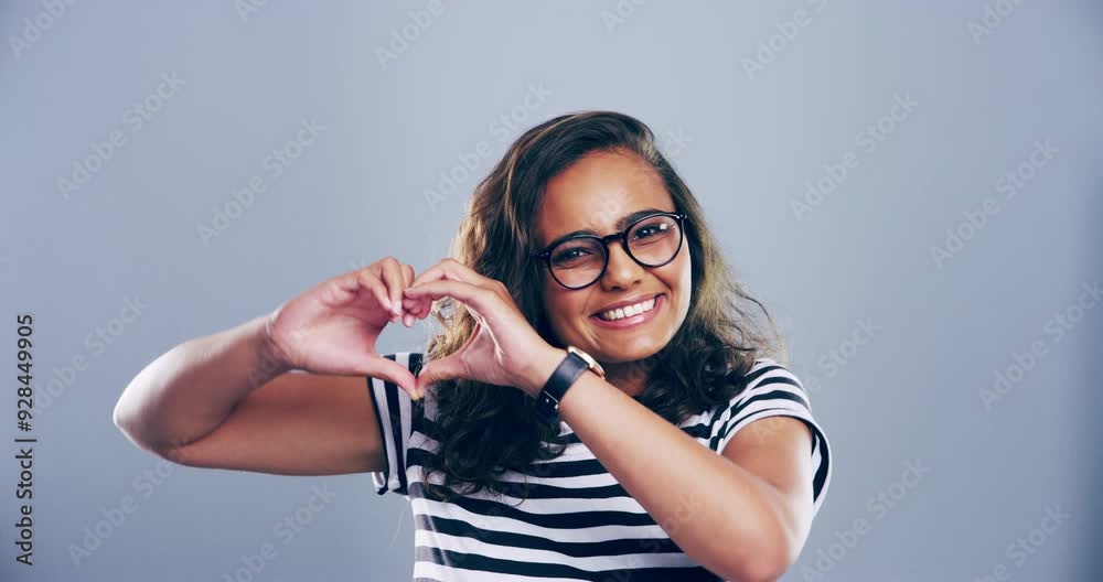 Heart hands, smile or woman in studio portrait in glasses for charity, peace or positive with kindness. Indian student, face and happy with sign for love, vision and hope emotion by grey background
