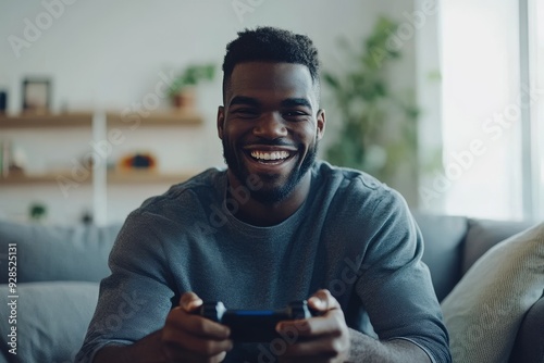 A young African American man playing a video game at home with a wireless game pad.