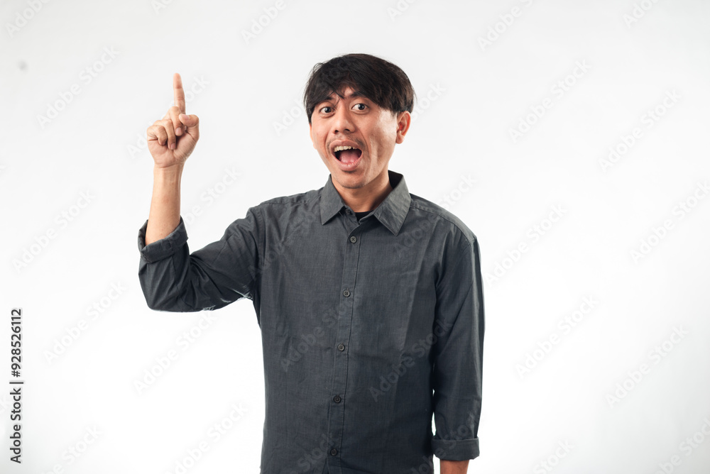 An enthusiastic Asian man in a gray shirt pointing upward with one hand while the other hand is on his hip. He has a wide, excited expression, standing against a plain white background. An enthusiastic Asian man in a gray shirt pointing upward with one hand while the other hand is on his hip. He has a wide, excited expression, standing against a plain white background.