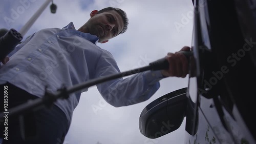 Man Charching Electric Car on Public Charching Station Using A Cable Connection  photo