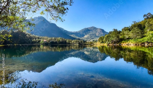 Reflection of mountains in a crystal clear lake and trees and blue sky for background with copy space