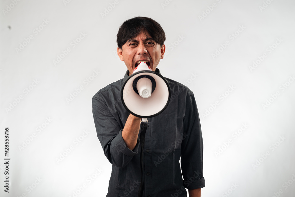 Asian man in a dark gray shirt passionately shouting into a megaphone, standing against a plain white background. The image conveys a sense of urgency, activism, or a call to action Asian man in a dark gray shirt passionately shouting into a megaphone, standing against a plain white background. The image conveys a sense of urgency, activism, or a call to action