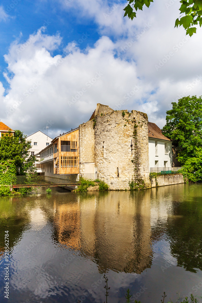 A historic stone tower in Montargis, France, beautifully reflected in the tranquil waters of the canal A historic stone tower in Montargis, France, beautifully reflected in the tranquil waters of the canal