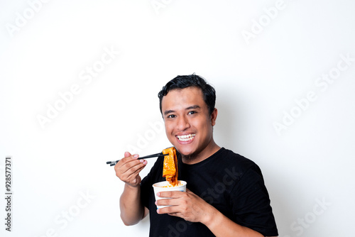 Asian adult man wearing a black t-shirt posing eating Korean specialty food odeng isolated white background photo