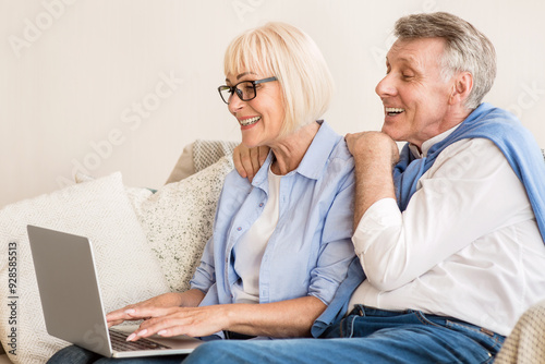 Modern gradparents. Loving couple chatting with grandchildren on laptop, having rest at home