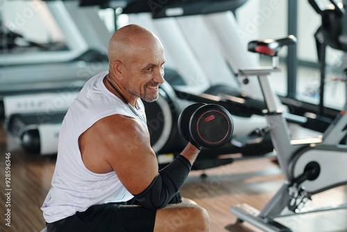 Muscular man exercising with dumbbells in wellness centre