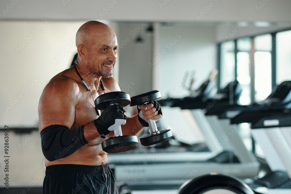 Muscular man exercising with dumbbells in sport gym Muscular man exercising with dumbbells in sport gym