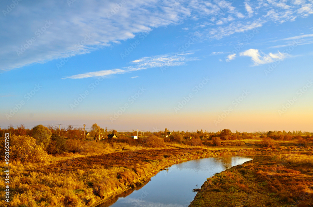 Obraz premium Autumn landscape. Small village at the bank of the river at the autumn evening in bright sunlight - autumn rural landscape in warm tone