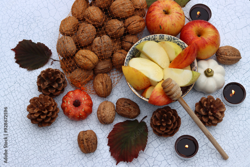 Autumn still life with apples, nuts, red leaves and candles on a table. Textured background with space for text. 