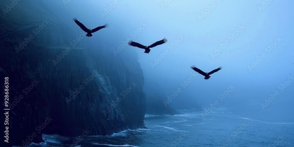 Naklejka premium Mysterious fog envelops a coastal landscape as three birds soar serenely against a backdrop of blue hues.