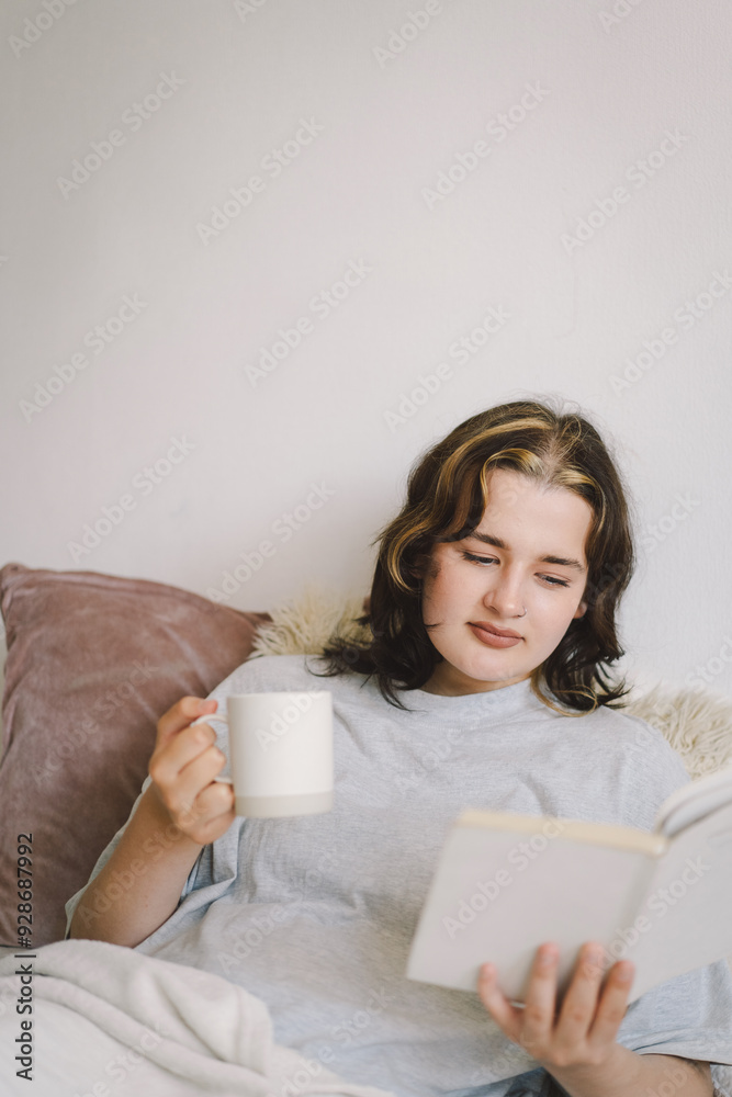 A woman relaxes on a couch, holding a mug and immersed in her reading, surrounded by a calm, inviting atmosphere. A woman relaxes on a couch, holding a mug and immersed in her reading, surrounded by a calm, inviting atmosphere.