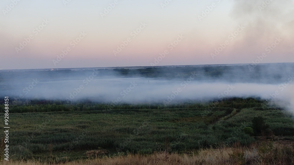Smoke from a fire over fields and valley in the evening Smoke from a fire over fields and valley in the evening