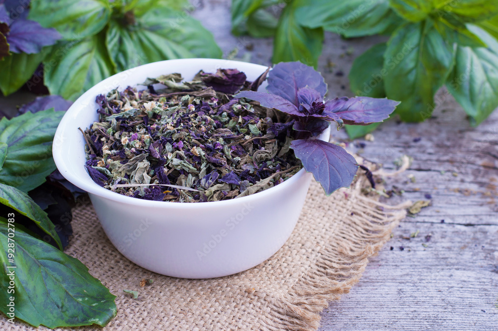 Dried basil in a bowl and fresh basil leaves on a wooden background. Horizontal, free space. Green and purple basil. Dried basil in a bowl and fresh basil leaves on a wooden background. Horizontal, free space. Green and purple basil.
