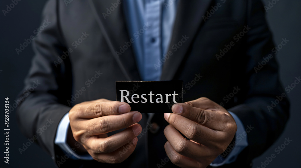 Businessman holds a black sign with the word restart in white letters Businessman holds a black sign with the word restart in white letters