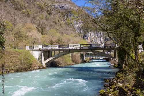 View on turbulent flow of a mountain river under bridge at springtime in Abkhazia, Georgia. Mountain landscape with two bridges over a rapid river on a sunny day