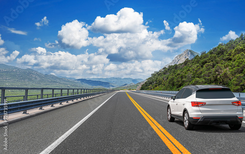 Obraz na płótnie The car is driving along the highway surrounded by picturesque nature. w salonie