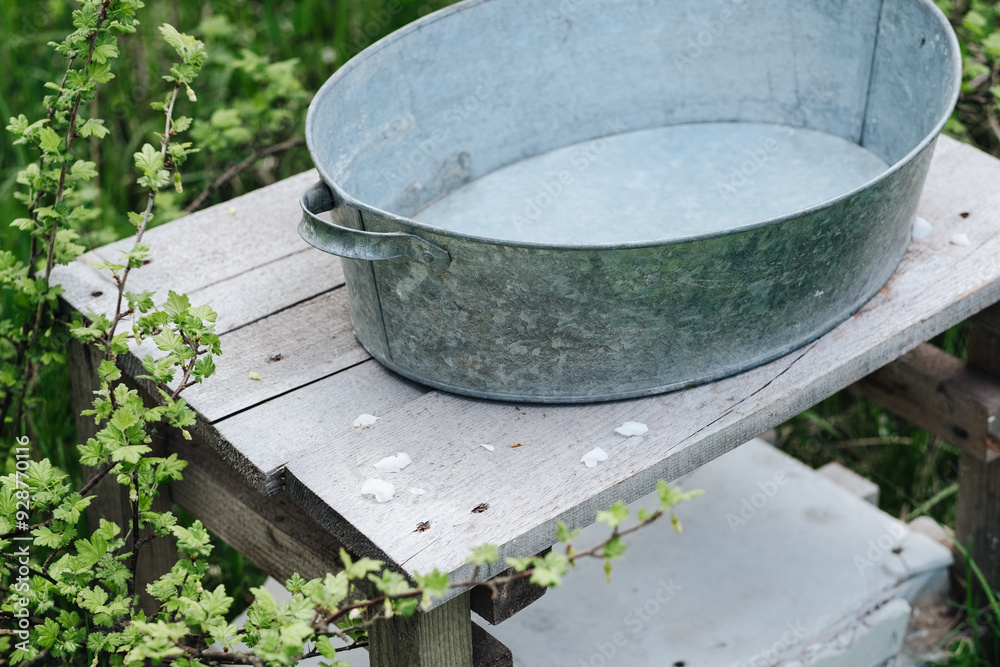 an iron bath basin stands on a table in the garden, under an apple tree an iron bath basin stands on a table in the garden, under an apple tree