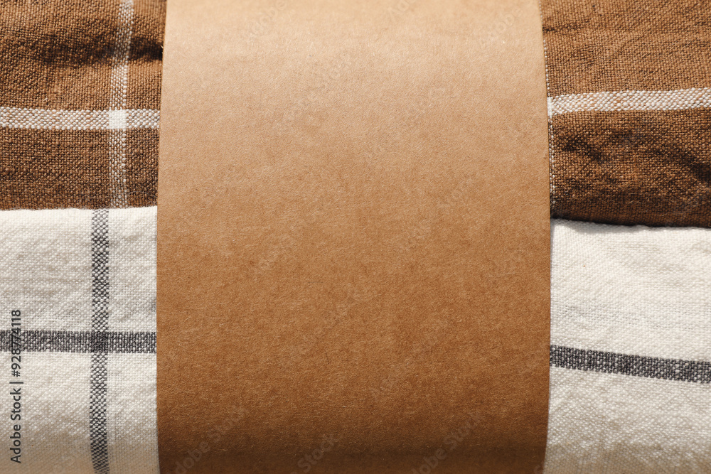 Fototapeta premium Pack of tea towels, dish clothes. Stack of checkered table clothes. Empty label mockup, paper band. Branding concept, banner. Closeup of textile napkins texture background.