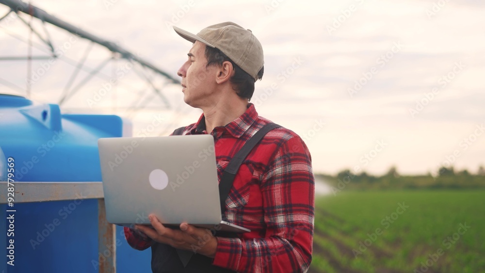irrigation agriculture. a male farmer works on a laptop in a field with corn. irrigation agriculture business concept. farmer scientist studying corn. lifestyle healthy natural foods concept irrigation agriculture. a male farmer works on a laptop in a field with corn. irrigation agriculture business concept. farmer scientist studying corn. lifestyle healthy natural foods concept