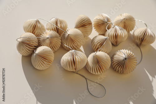 Elegant Christmas ornaments decor. Glittering white paper Christmas balls, baubles isolated on beige table background. Festive winter banner. Flat lay, top view. No people, copy space. Selective focus