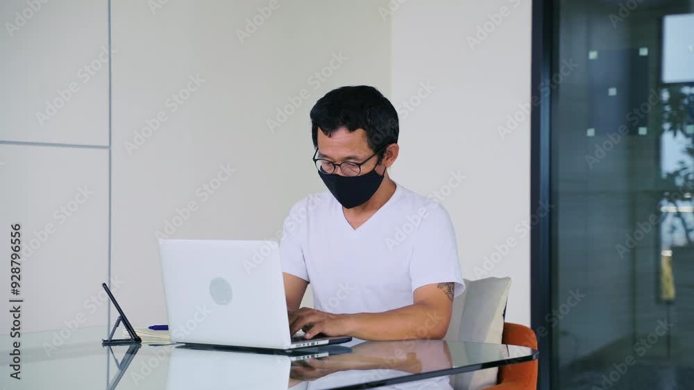Asian man wearing face mask sitting at work in working space Asian man wearing face mask sitting at work in working space