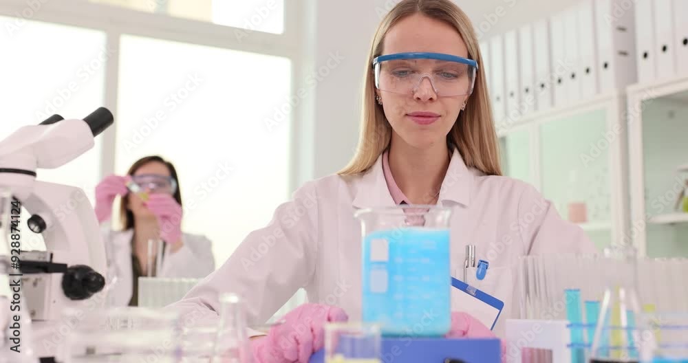 Female scientist working in a laboratory with blue liquid Female scientist working in a laboratory with blue liquid