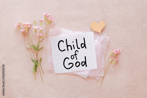 I am a child of God - christian text on card with little flowers and heart on light pink background, biblical verse and religion concept photo