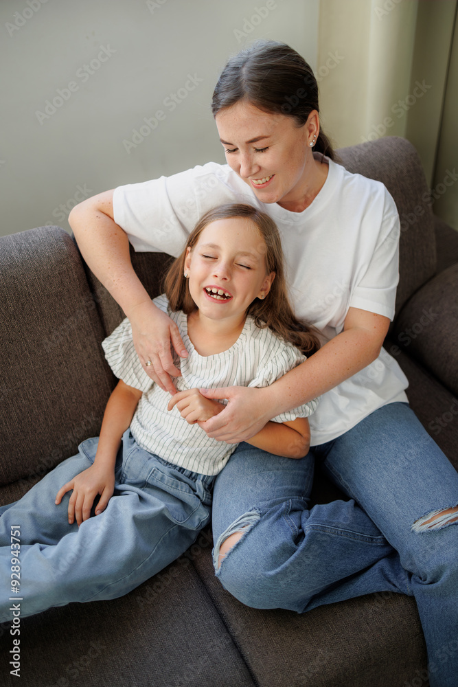 Smiling mother and daughter spending time on couch at home Smiling mother and daughter spending time on couch at home
