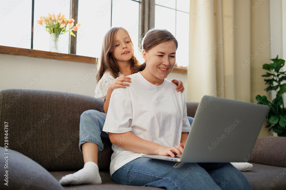 Smiling girl hugging mother with laptop at home Smiling girl hugging mother with laptop at home