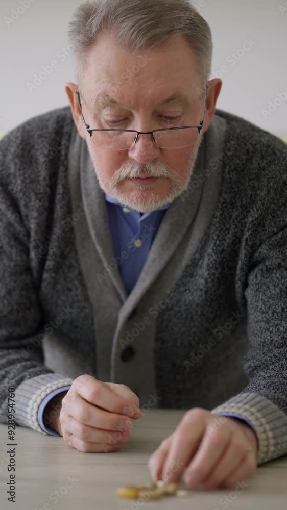 Senior man taking pills from table, vertical video portrait, healthcare in old age. Sick aged male person curing his diseases, preventing illness and keeping good feeling. Aging-associated diseases Senior man taking pills from table, vertical video portrait, healthcare in old age. Sick aged male person curing his diseases, preventing illness and keeping good feeling. Aging-associated diseases